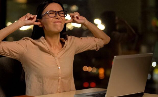 woman covering ears irritated with noise in office