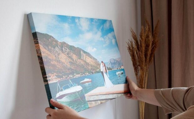 woman hangs wedding photography on white wall