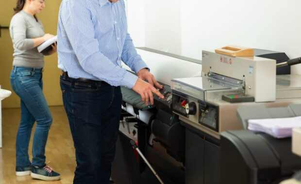 man uses plotter in small format printing shop