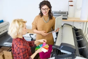 portrait of two graphic designers standing by plotter machine in printing shop
