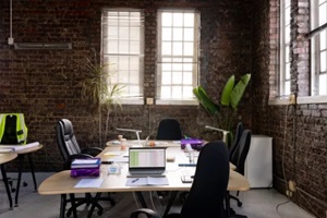 modern creative office interior with exposed brick wall textured covering, desks and chairs